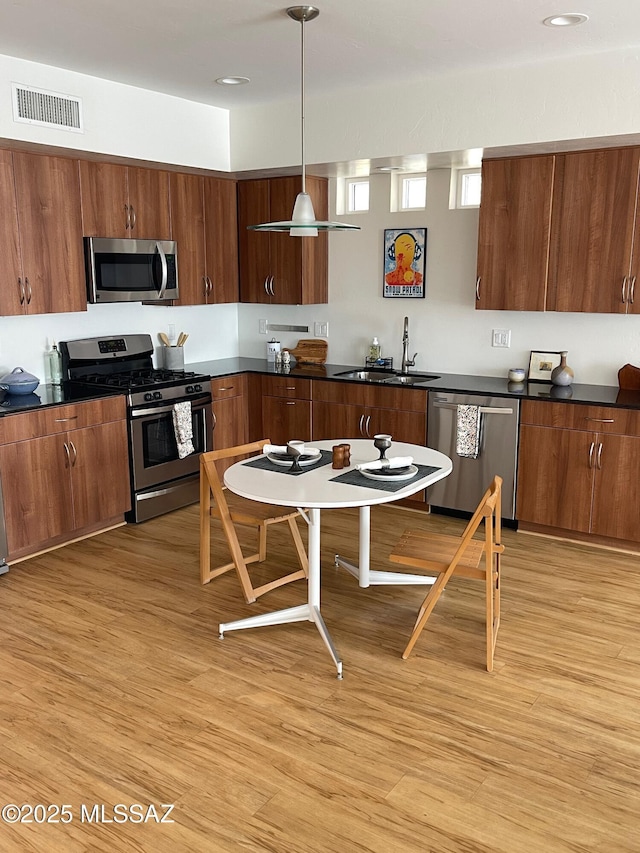 kitchen featuring visible vents, dark countertops, a sink, and stainless steel appliances