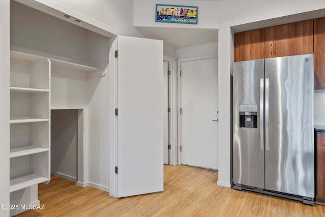interior space with stainless steel fridge, open shelves, light wood finished floors, and brown cabinets