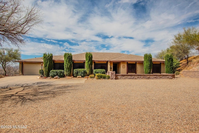 ranch-style home with stucco siding, driveway, and a garage