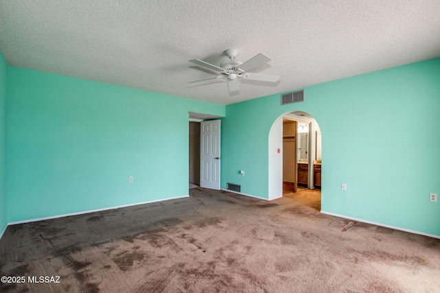 unfurnished bedroom featuring carpet floors, arched walkways, and visible vents