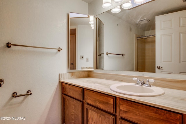 bathroom featuring an enclosed shower, visible vents, and vanity