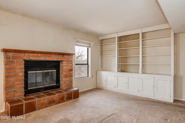 unfurnished living room with a textured ceiling, carpet, baseboards, a fireplace, and built in shelves