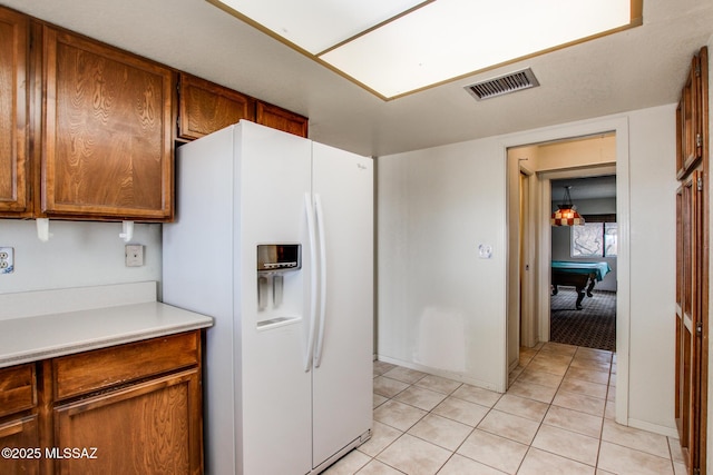 kitchen featuring light countertops, white refrigerator with ice dispenser, light tile patterned flooring, visible vents, and pool table