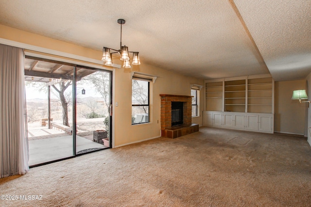 unfurnished living room with a textured ceiling, carpet floors, a fireplace, and a notable chandelier