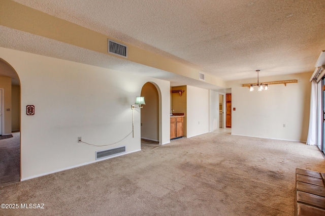 interior space featuring light carpet, visible vents, and arched walkways