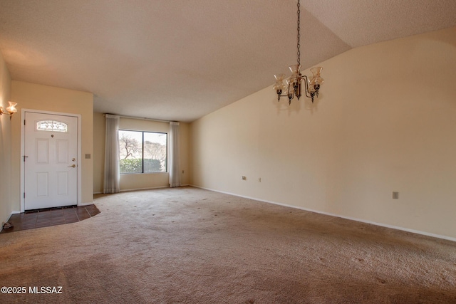 carpeted foyer featuring baseboards, lofted ceiling, a textured ceiling, and a notable chandelier
