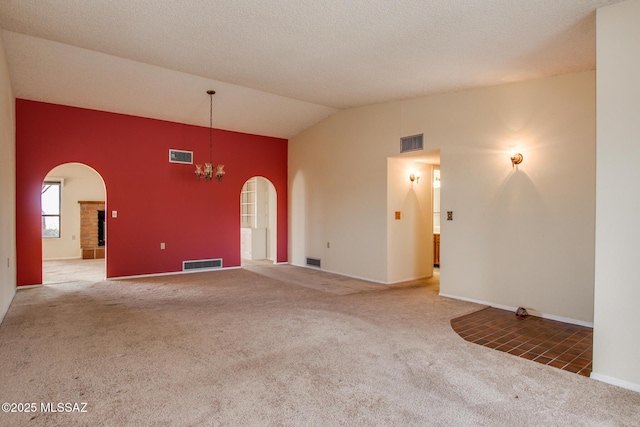 empty room with arched walkways, visible vents, vaulted ceiling, and carpet