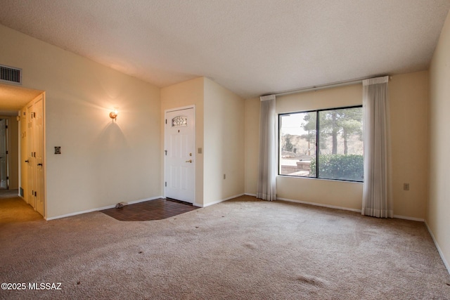carpeted spare room featuring a textured ceiling, baseboards, vaulted ceiling, and visible vents