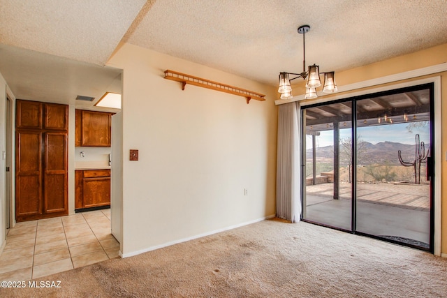 spare room with baseboards, a textured ceiling, and light colored carpet