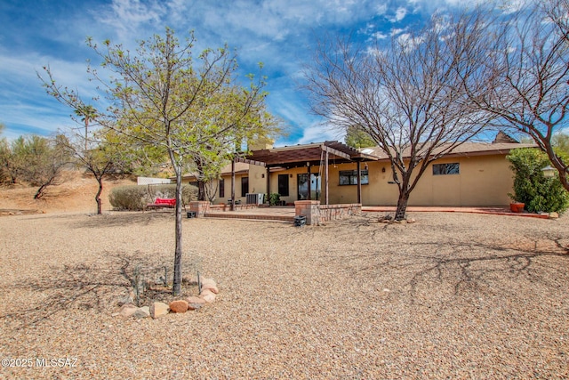 view of front facade featuring stucco siding, a patio, and a pergola