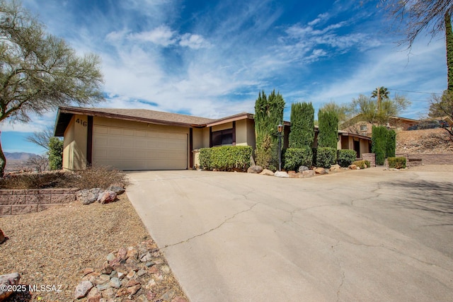 view of front of home featuring driveway, an attached garage, and stucco siding