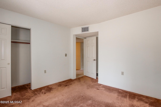unfurnished bedroom featuring a closet, carpet floors, a textured ceiling, and visible vents