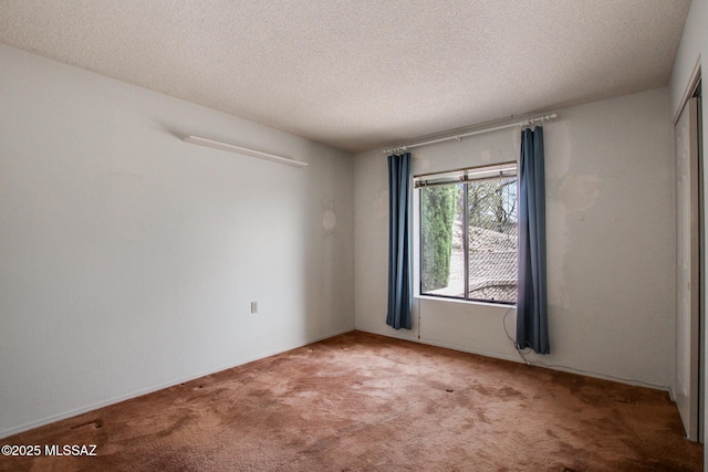 carpeted empty room featuring a textured ceiling