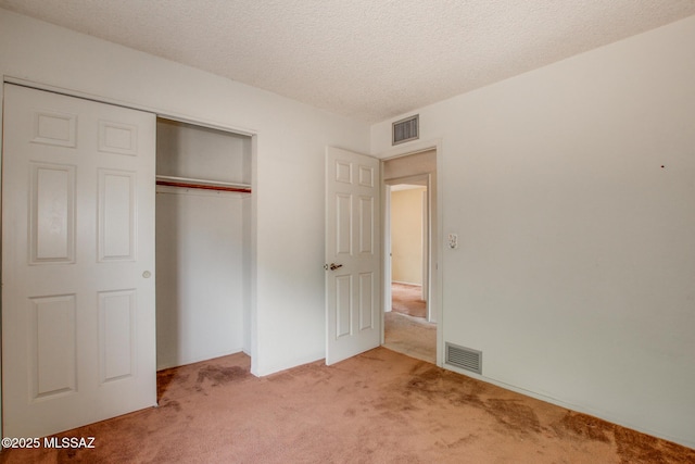 unfurnished bedroom featuring light carpet, a textured ceiling, a closet, and visible vents