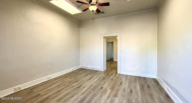 spare room with a ceiling fan, wood finished floors, baseboards, and visible vents