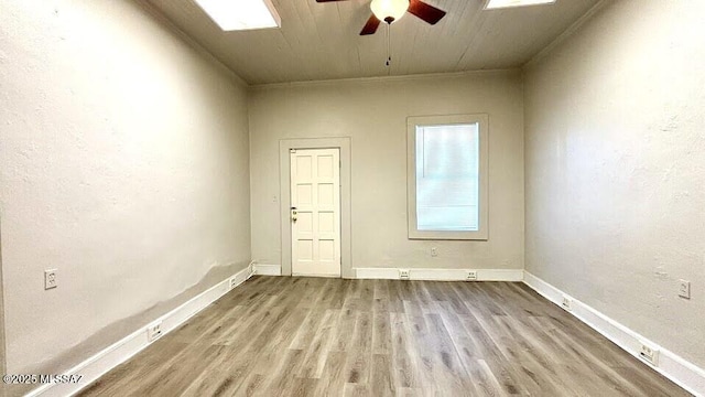 spare room with baseboards, wood finished floors, and ceiling fan