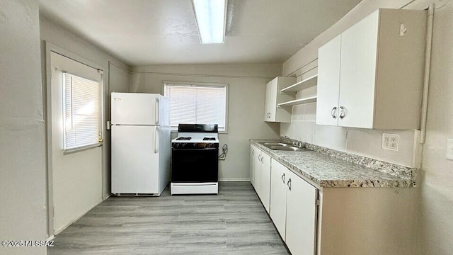 kitchen featuring a sink, open shelves, freestanding refrigerator, stove, and white cabinets