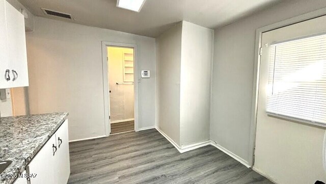 interior space featuring white cabinets, light stone countertops, dark wood finished floors, and visible vents