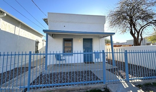 view of front facade featuring stucco siding, a porch, a gate, and a fenced front yard