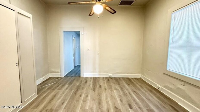 unfurnished bedroom featuring wood finished floors, a closet, baseboards, and visible vents