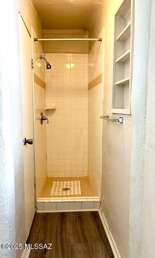bathroom with tiled shower and wood finished floors