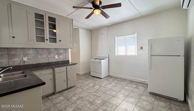 kitchen featuring a wall mounted air conditioner, white appliances, dark countertops, a ceiling fan, and a sink