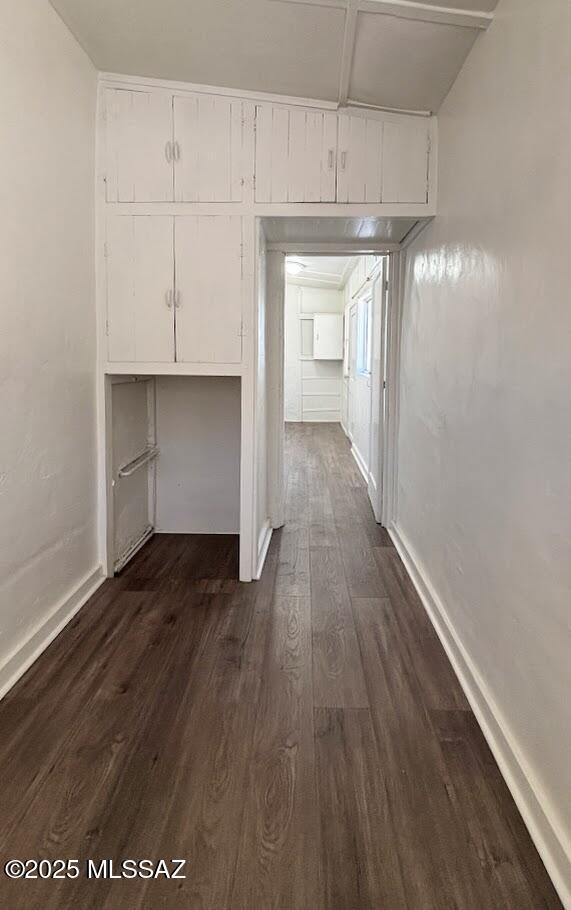 hallway with baseboards and dark wood-style flooring