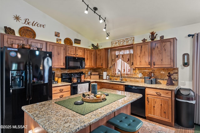 kitchen with tasteful backsplash, black appliances, a center island, a sink, and lofted ceiling