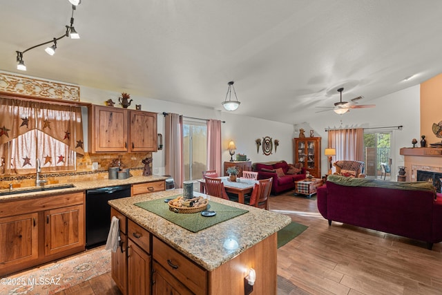 kitchen with brown cabinets, a sink, black dishwasher, and a healthy amount of sunlight