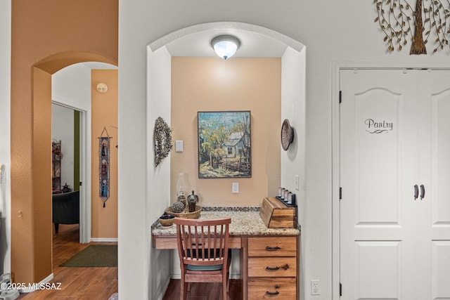 interior space featuring dark wood-type flooring, arched walkways, and baseboards