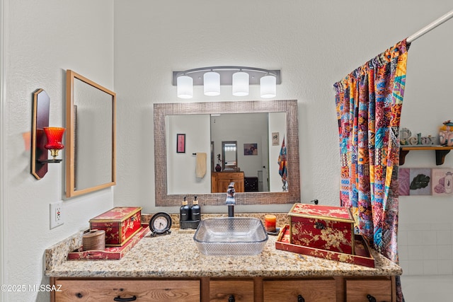 full bathroom with vanity and a textured wall