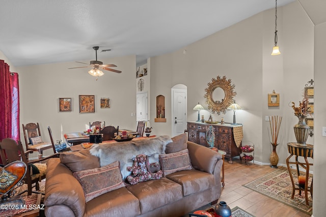 living room with vaulted ceiling, a ceiling fan, visible vents, arched walkways, and wood finished floors