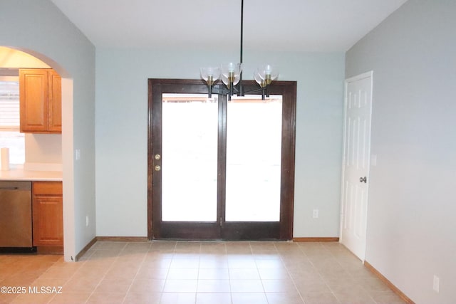 unfurnished dining area with light tile patterned floors, arched walkways, a chandelier, and a wealth of natural light