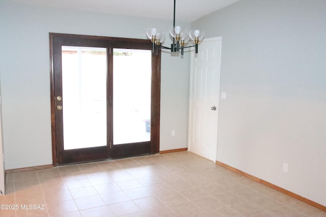 empty room featuring an inviting chandelier, light tile patterned floors, and baseboards