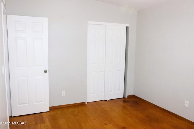 unfurnished bedroom featuring baseboards, a closet, and wood finished floors