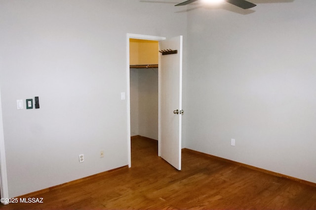 unfurnished bedroom featuring a spacious closet, light wood-style flooring, baseboards, and a closet