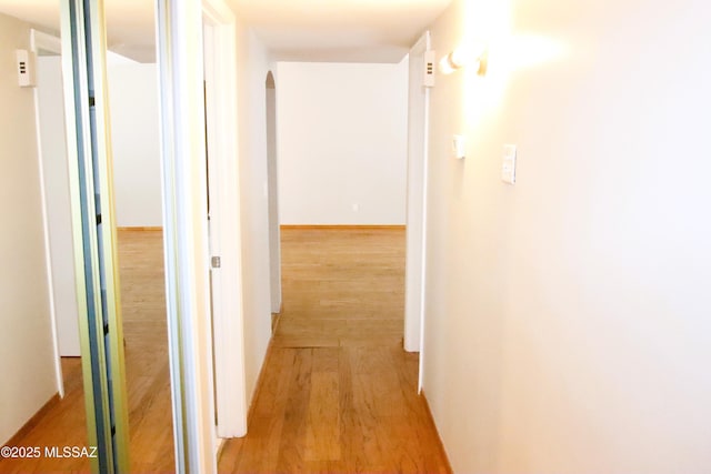 hall featuring arched walkways and light wood-style flooring