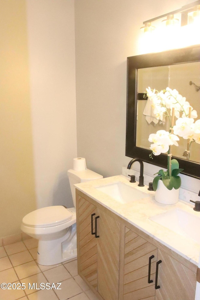 bathroom featuring tile patterned floors, toilet, double vanity, and a sink