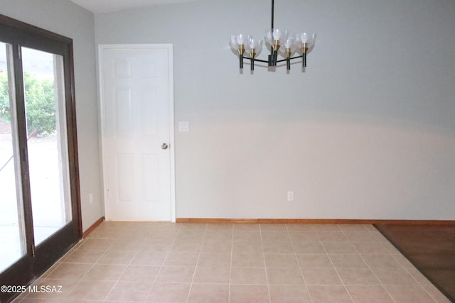 empty room with baseboards, light tile patterned floors, and an inviting chandelier