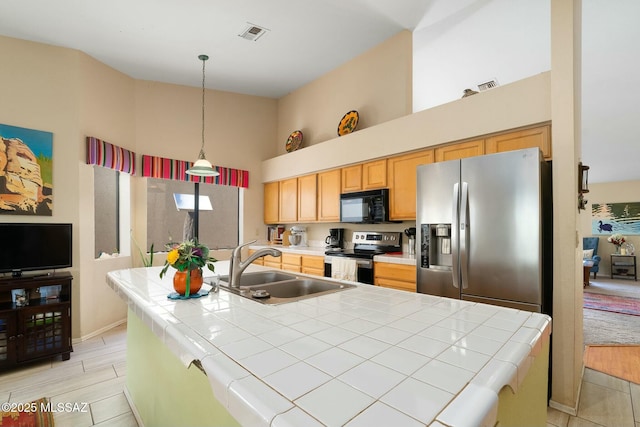 kitchen with visible vents, a sink, stainless steel appliances, pendant lighting, and tile countertops