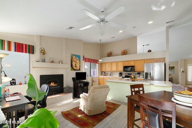 dining area with a large fireplace, visible vents, ceiling fan, and high vaulted ceiling