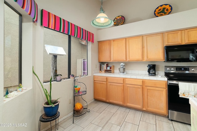 kitchen featuring stainless steel range with electric stovetop, black microwave, and light brown cabinetry