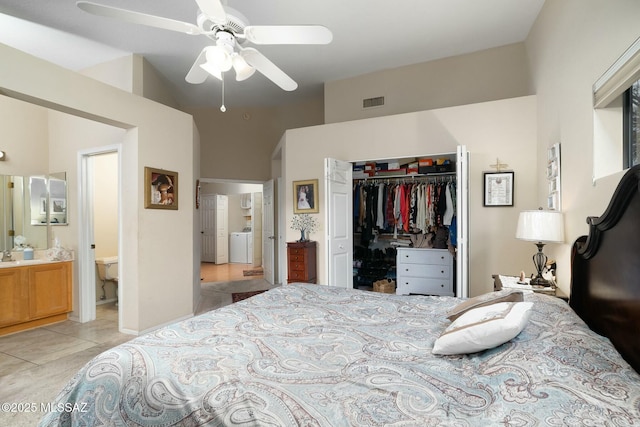 bedroom with a closet, ensuite bath, vaulted ceiling, washing machine and dryer, and light tile patterned flooring