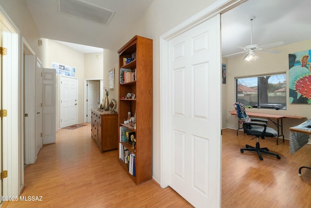 corridor featuring light wood finished floors, vaulted ceiling, and visible vents
