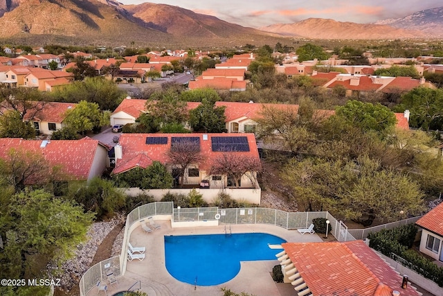 pool featuring a mountain view, fence, a patio, and a residential view