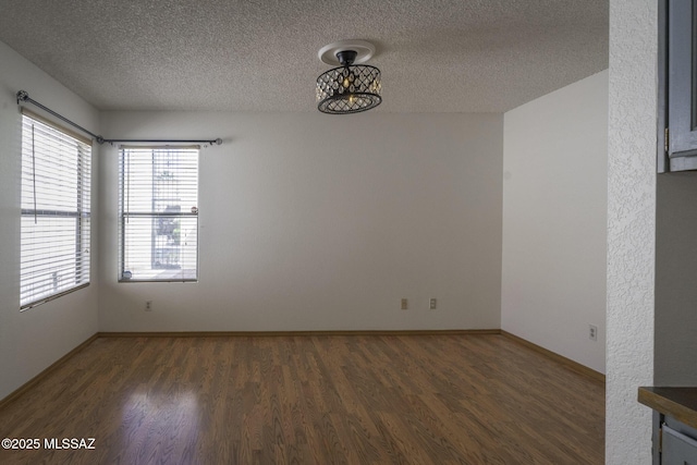 empty room with baseboards, a textured ceiling, and wood finished floors