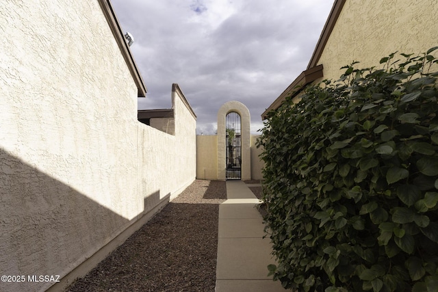 view of exterior entry featuring a gate, stucco siding, and fence
