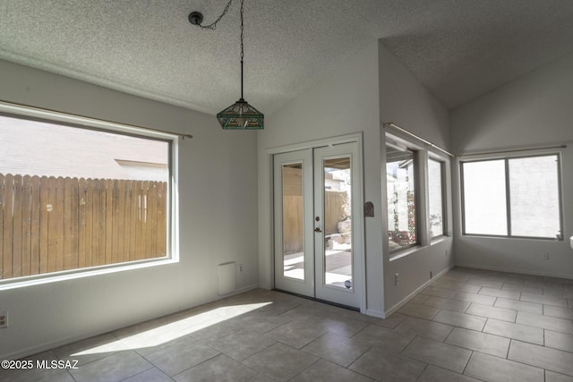 interior space with french doors, tile patterned floors, vaulted ceiling, and a textured ceiling