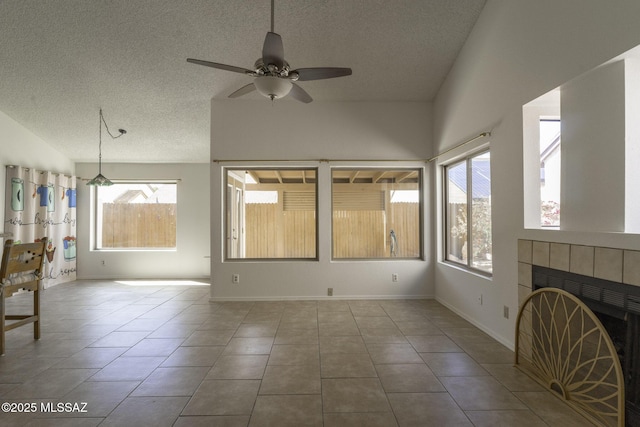 unfurnished living room featuring lofted ceiling, a textured ceiling, tile patterned floors, and a ceiling fan