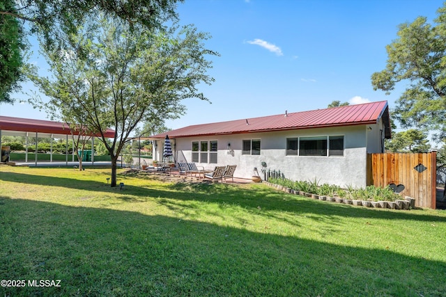 back of house with fence, metal roof, a yard, and stucco siding